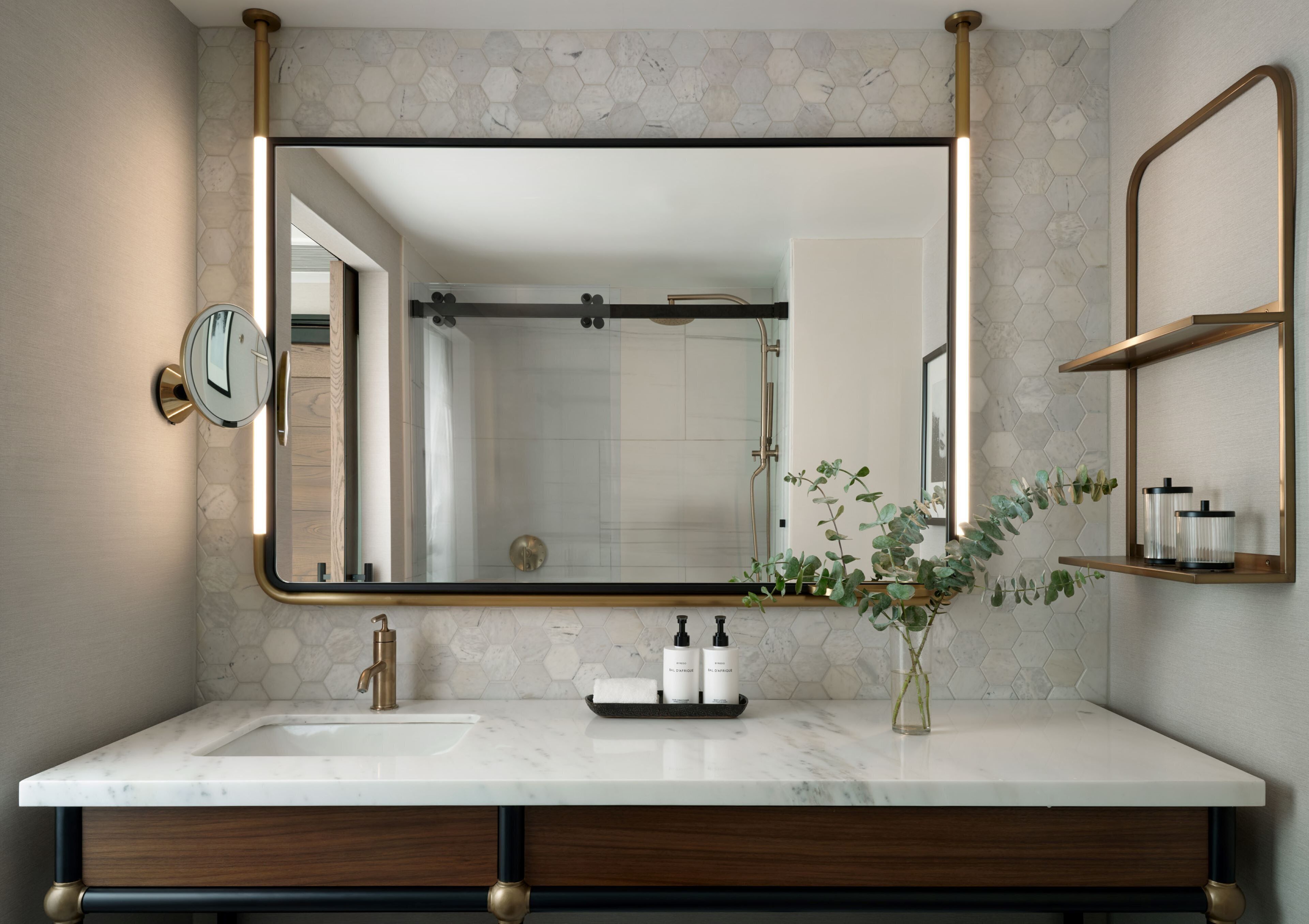 A bathroom with a large mirror, a sink, and a shower.