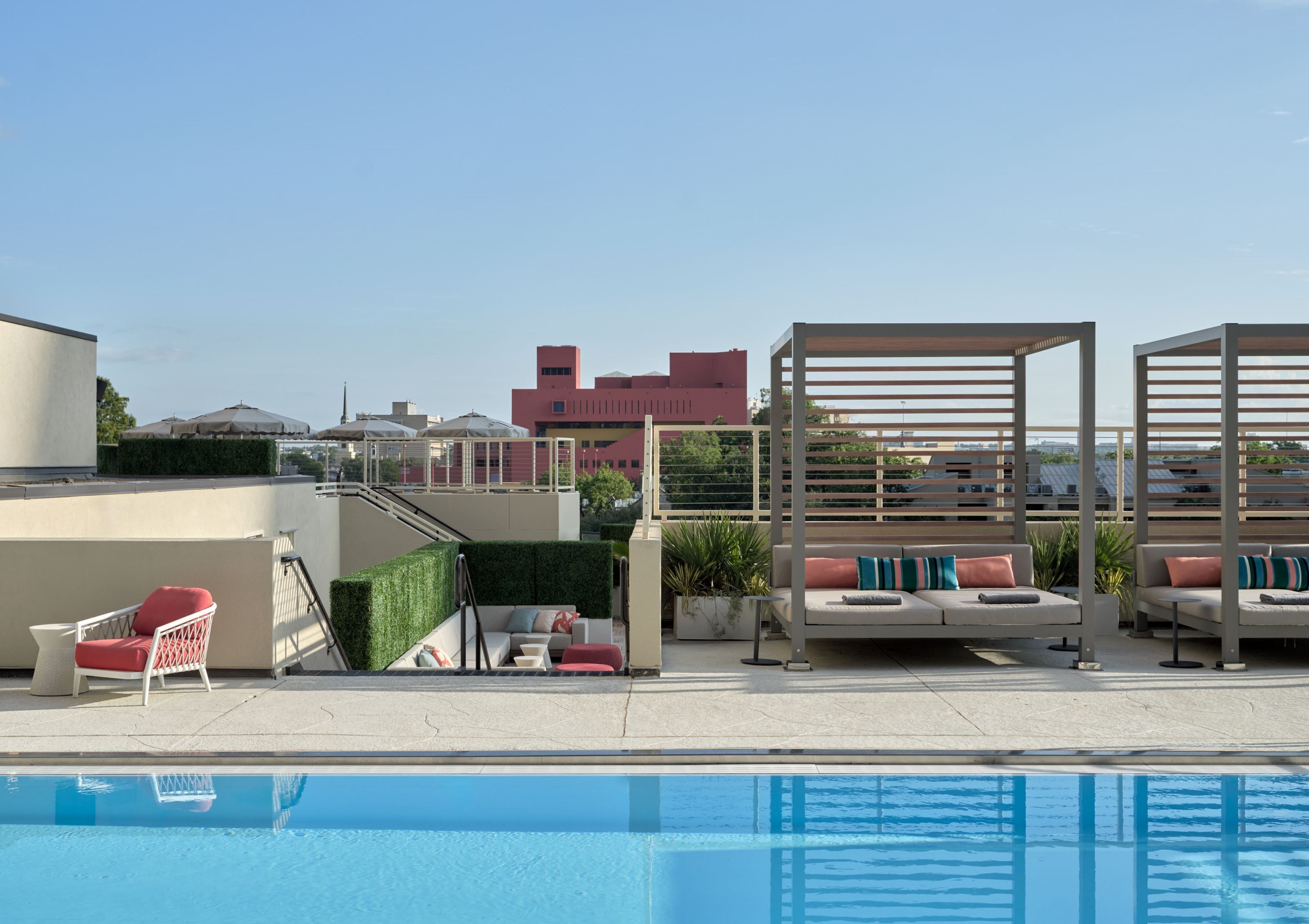 Un espace piscine aménagé sur le toit, avec des chaises longues, une petite table et une structure en forme de pergola.