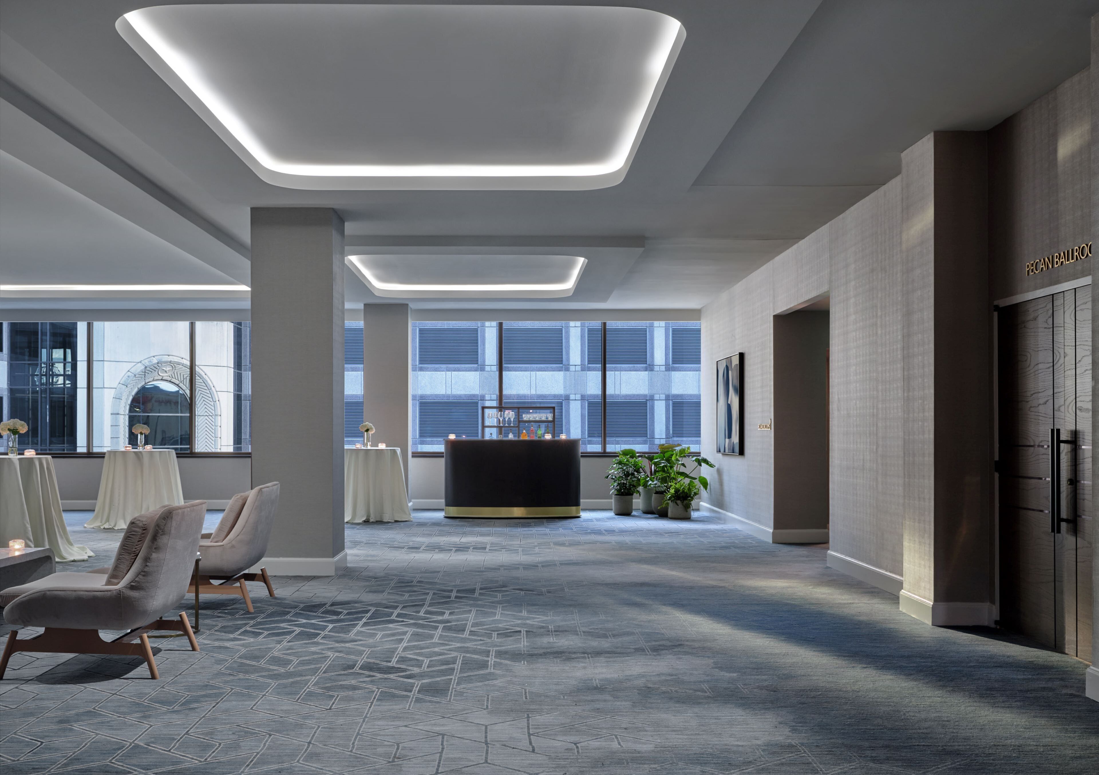 Un lobby moderno de hotel con mostrador de recepción, zona de estar y ventanas amplias.