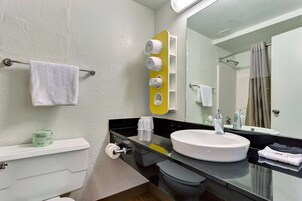 Bañera con ducha, toallas, jabón, shampoo