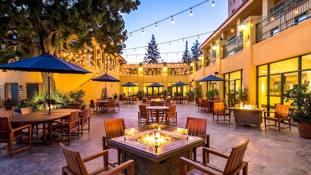An outdoor patio area with tables and chairs, string lights, and a fire pit.