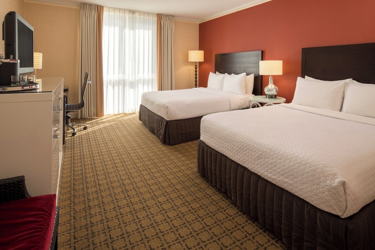 Een hotelkamer met twee bedden, een bureau met een computer en een televisie.