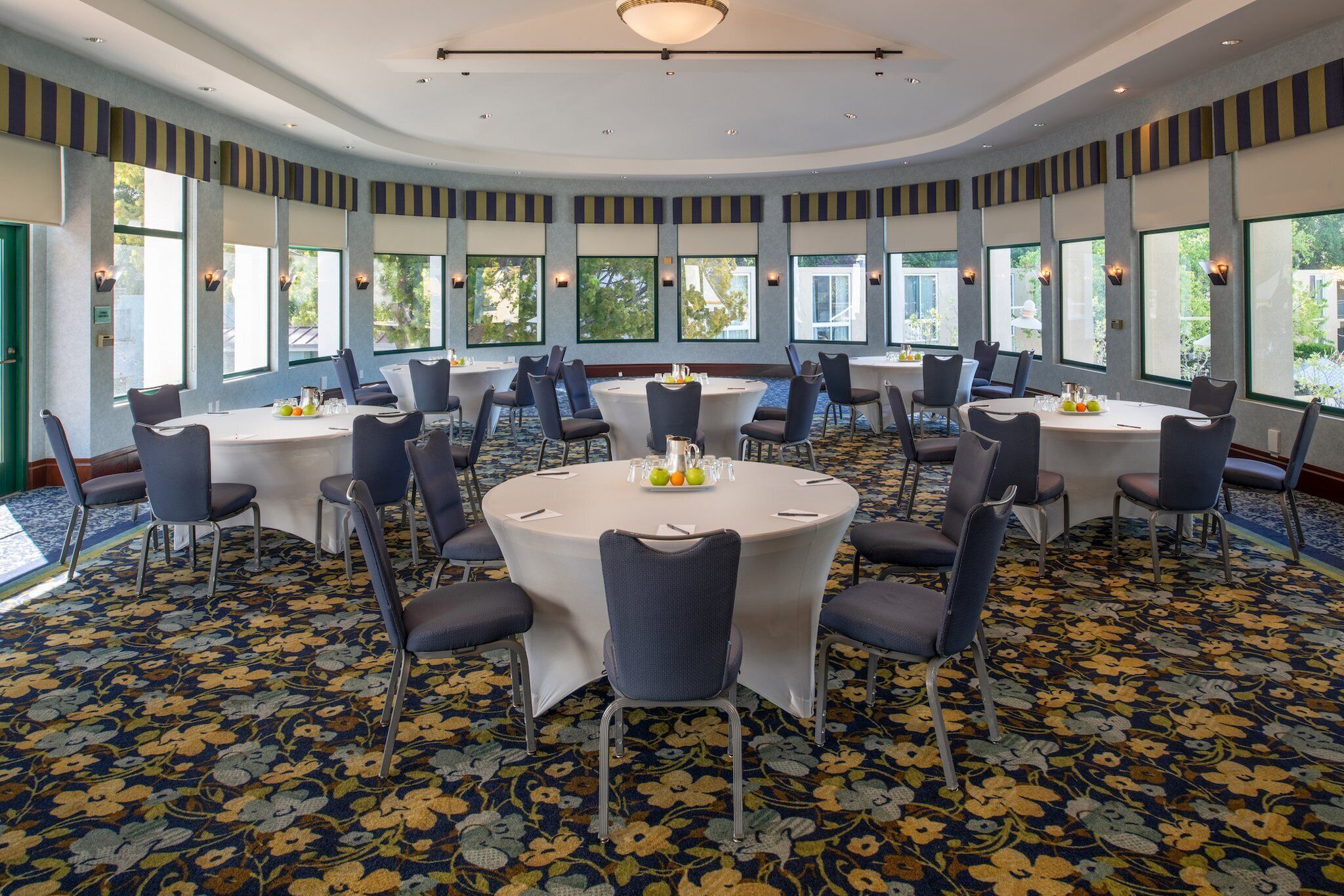 A conference room with round tables, chairs, and large windows.