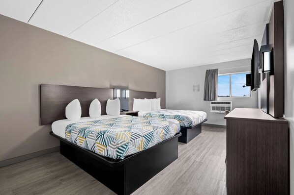 A modern hotel room with two beds, a flat-screen TV, an air conditioning unit, and a window with a view.