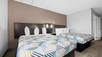 A hotel room with two beds, a dark headboard, and a light-colored wall.