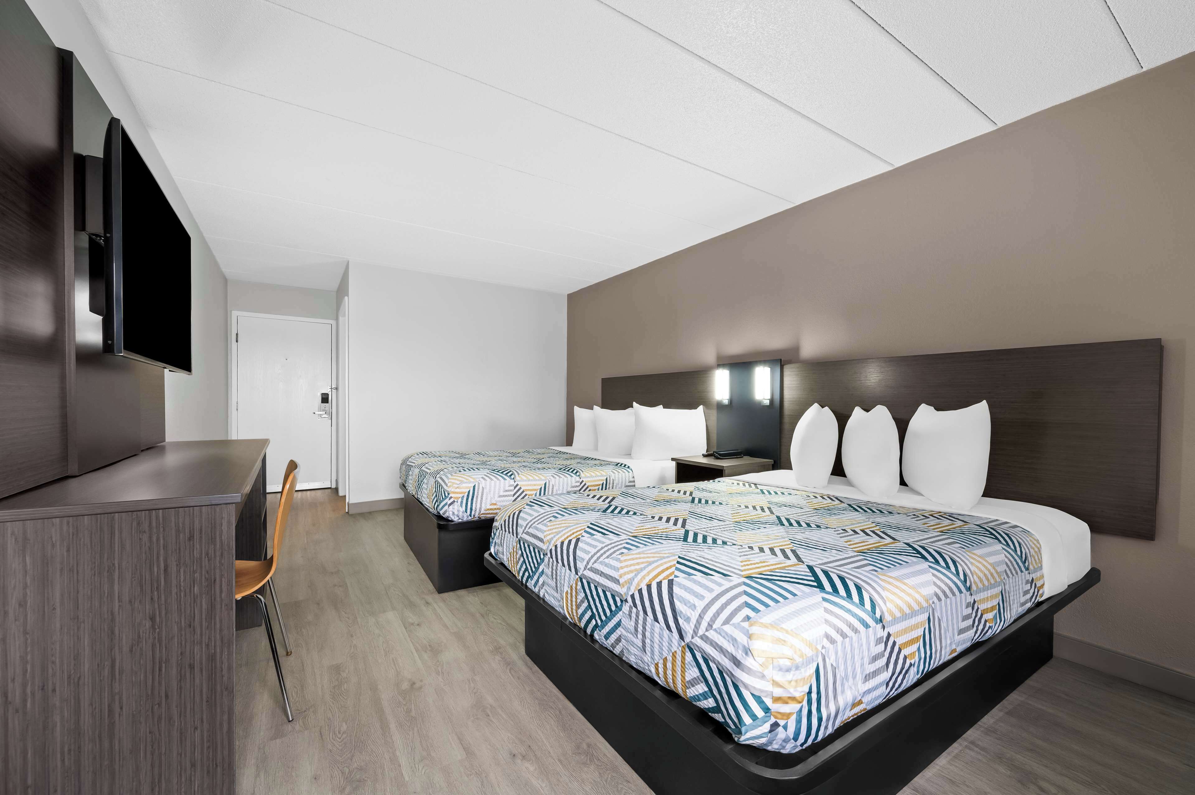 Habitación de hotel con dos camas, un escritorio, un televisor de pantalla plana y un diseño moderno.