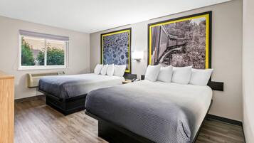 A hotel room with two beds, a window, and two framed pictures on the wall.