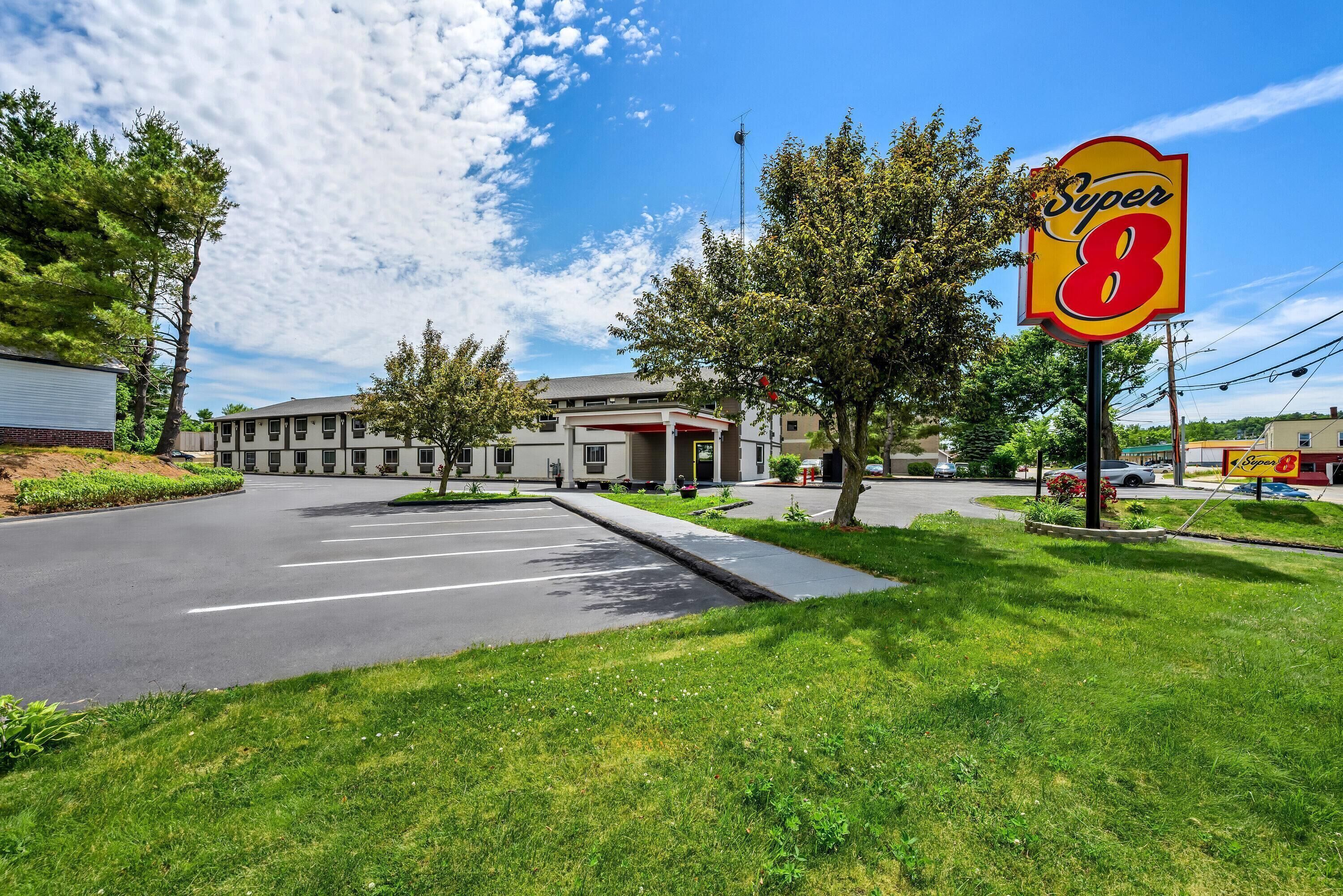 Un motel de type Super 8 avec un parking, un bâtiment doté d’une marquise rouge et un ciel d’un bleu éclatant.