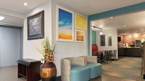 A modern lobby with a seating area, a large vase with flowers, and framed pictures on the wall. - Days Inn by Wyndham Fort Smith (Fort Smith)