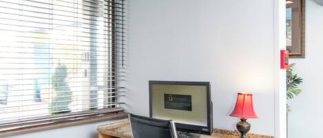 Un espacio de oficina moderno con un escritorio de madera, una silla de oficina negra, una computadora y una lámpara roja.