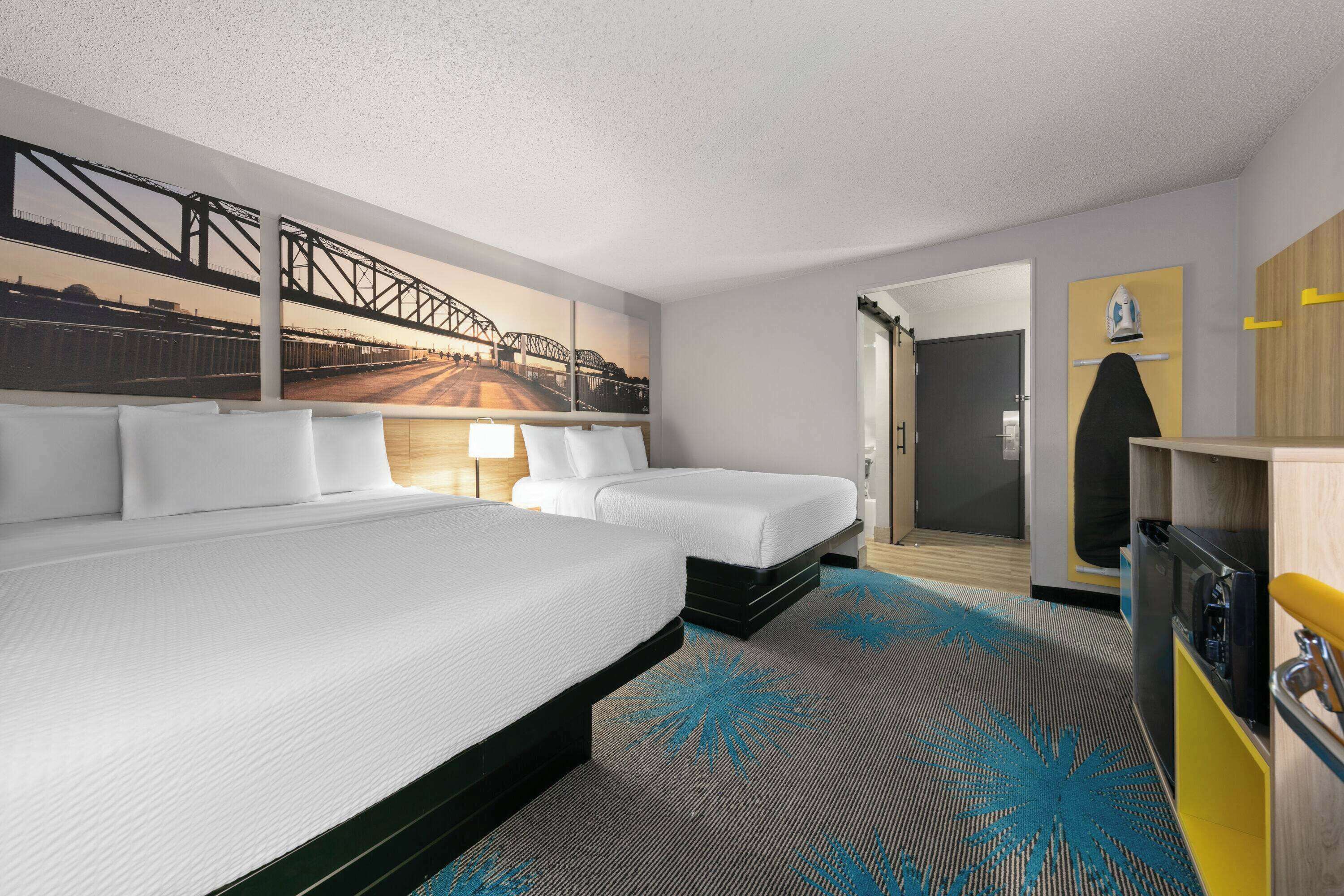 A hotel room with a large bed, a smaller bed, a desk, and a wardrobe.