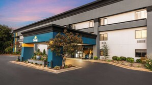 A modern hotel with a flat roof, large windows, and a landscaped entrance area with a tree and seating. - Days Inn by Wyndham Fort Smith (Fort Smith)