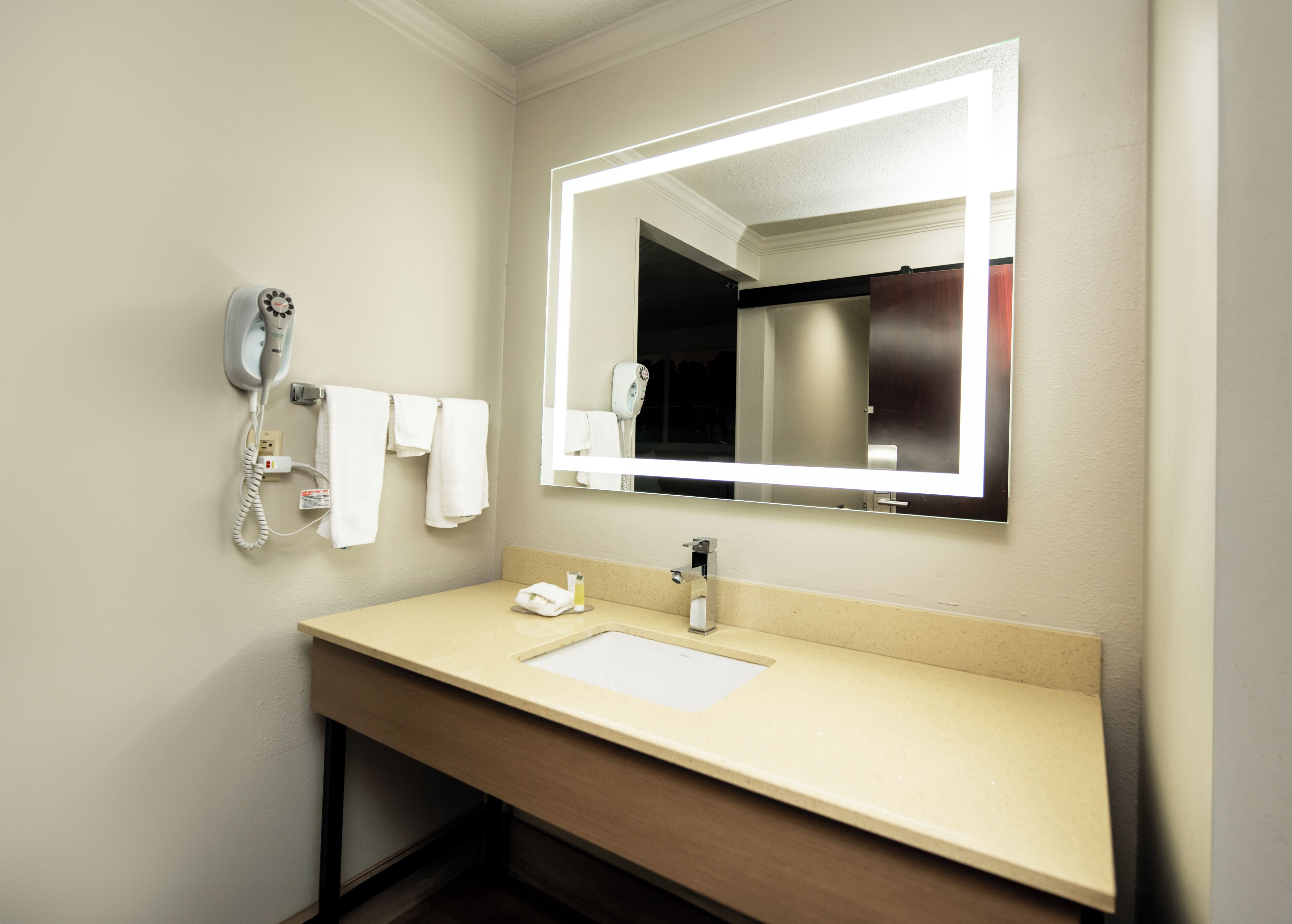 Un baño de hotel con lavamanos, espejo y teléfono.