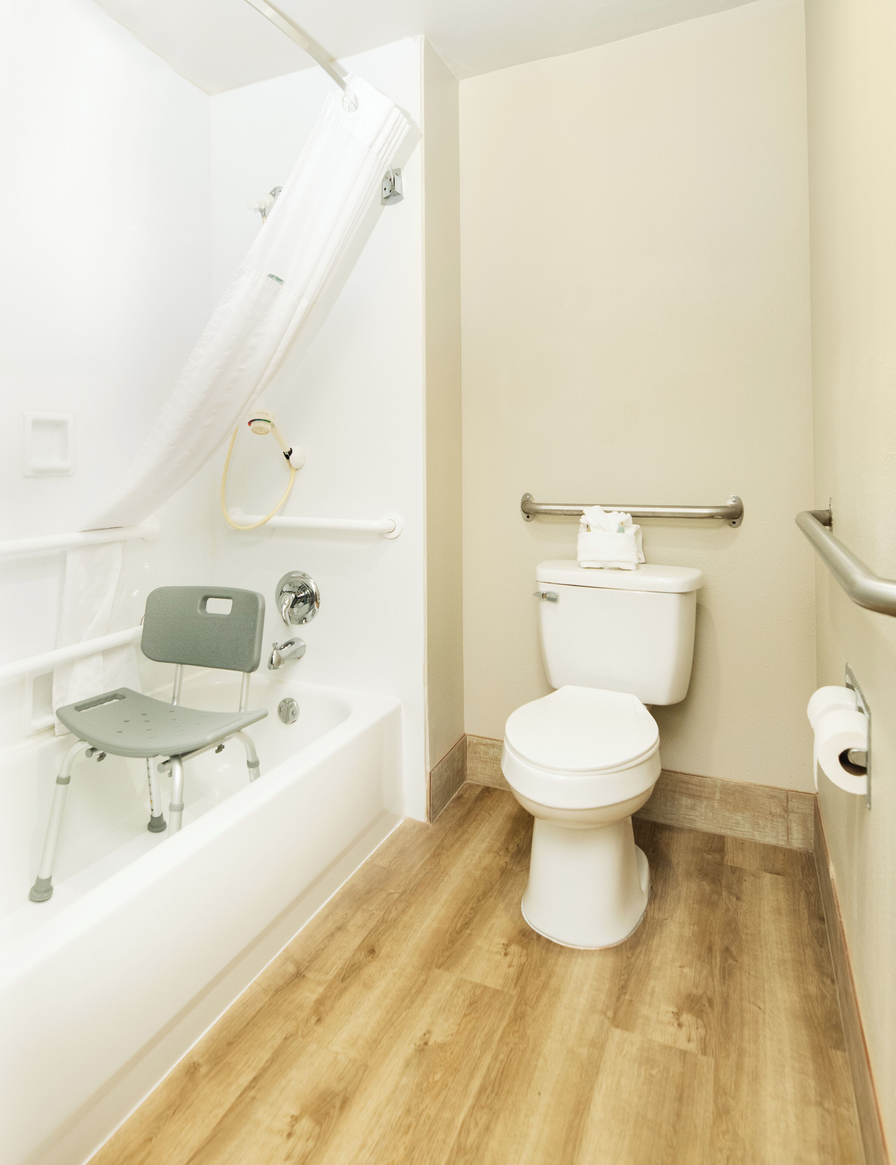 A bathroom with a bathtub, a shower, a toilet, and a grab bar.