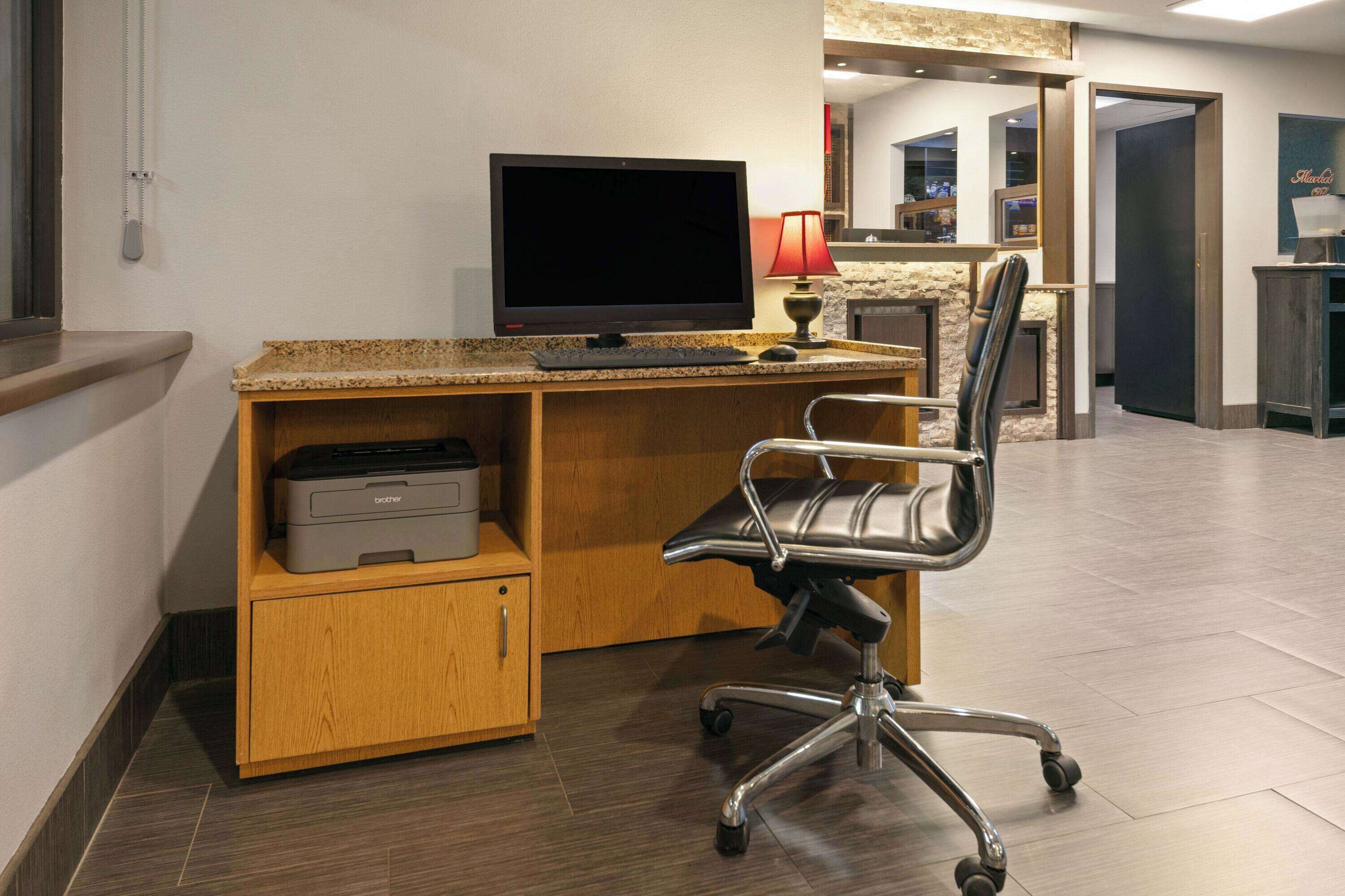 Un espace de bureau moderne comprenant un bureau, une chaise, une imprimante et un écran plat.