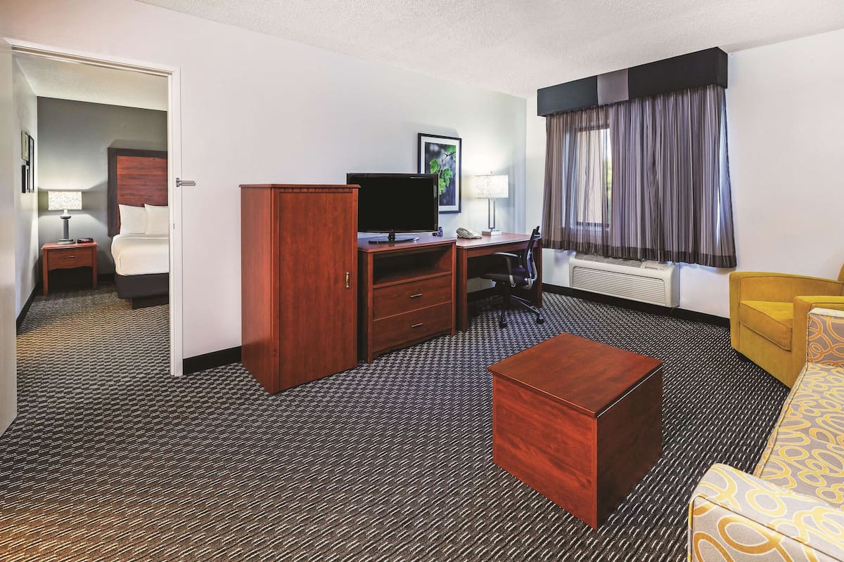 A hotel room with a bed, desk, television, and a sofa.