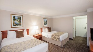 A hotel room with two beds, a nightstand with a lamp, a television, and two framed pictures on the wall. - Baymont by Wyndham Texarkana (Texarkana)