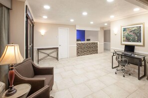 Une chambre d’hôtel avec un canapé, une petite table, un bureau avec un ordinateur, une lampe et un tableau au mur.