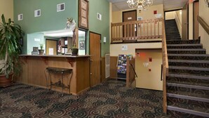 A lobby with a reception desk, a staircase, and a chandelier. - Super 8 by Wyndham Russellville (Russellville)