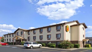A hotel with a beige exterior, multiple windows, and a parking lot with two cars. - Super 8 by Wyndham Russellville (Russellville)