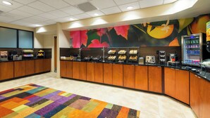 A breakfast bar with a variety of food items, a fruit-themed wall mural, and a vending machine.