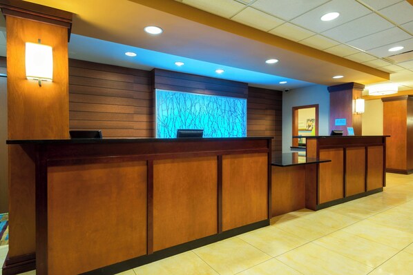 Un área de recepción con un mostrador de madera, una pared iluminada en azul y un piso de baldosas.