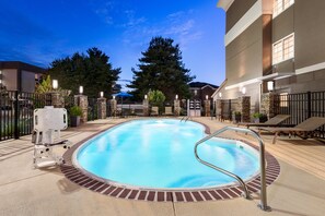 A swimming pool with a brick border, lounge chairs, and a stone wall with a gate. - Holiday Inn Express Bowling Green by IHG (Bowling Green)