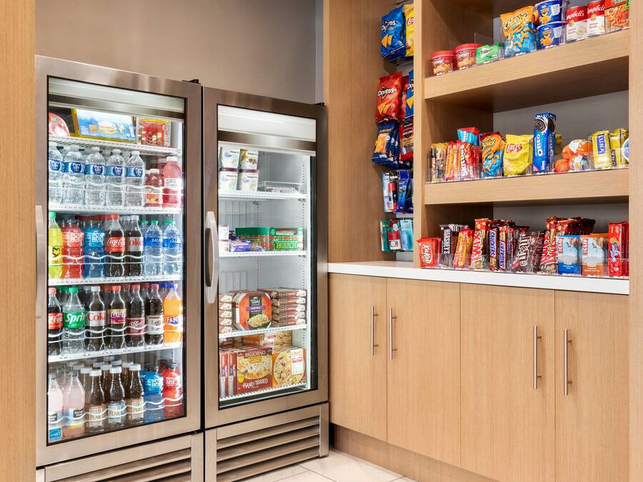 A self-service beverage and snack area with refrigerated drinks and a variety of snacks on shelves.