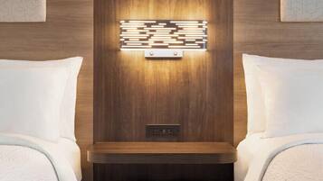 A hotel room with a wooden headboard, a bedside table, and a wall-mounted light fixture.