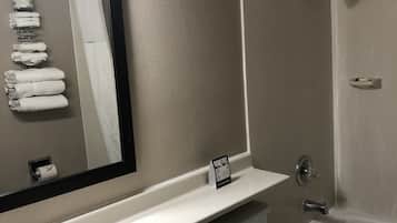A bathroom with a sink, toilet, and shower. There is a towel rack with towels, a mirror, and a sign indicating the room is free.