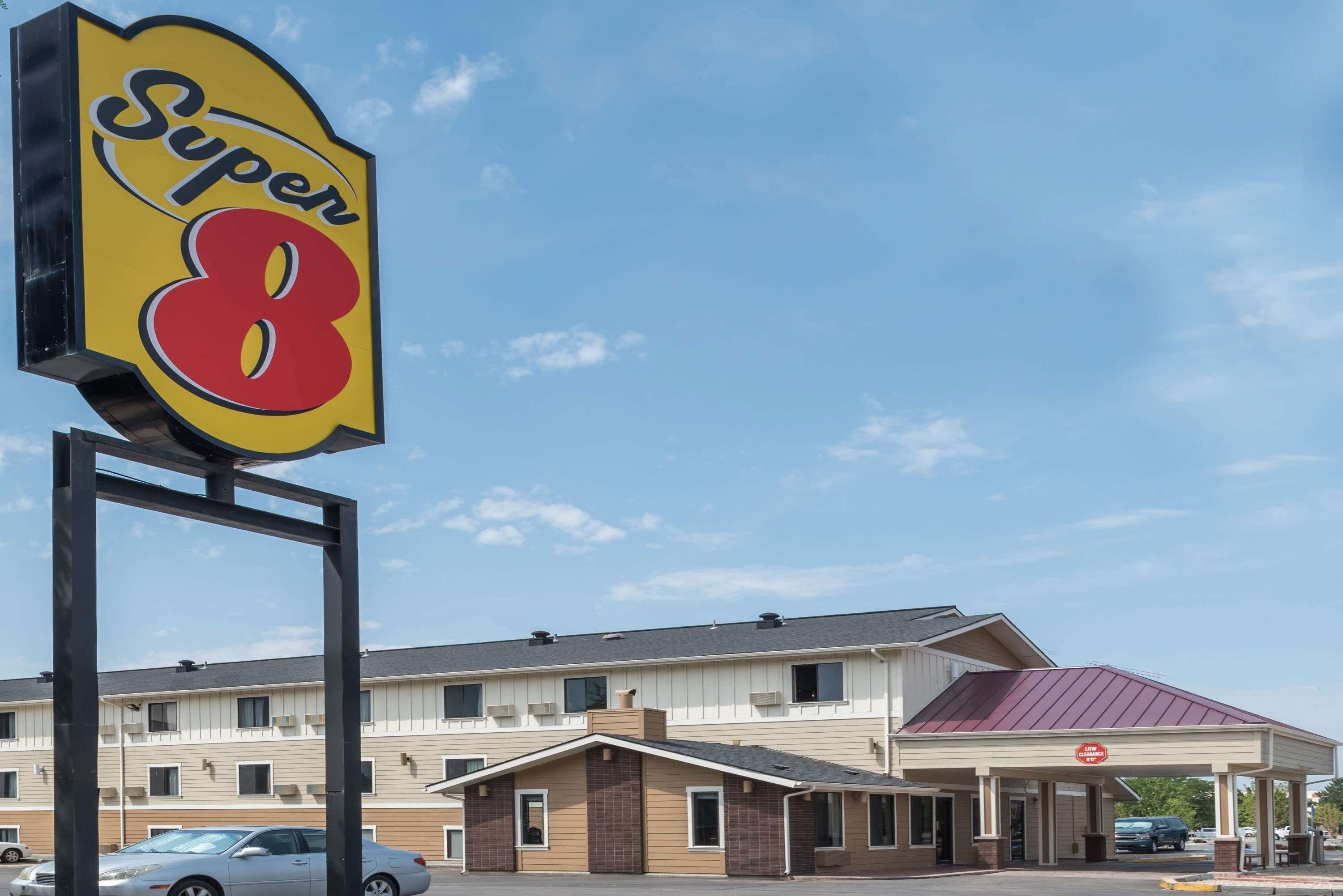 A hotel with a prominent 'Super 8' sign, a covered parking area, and a building with multiple windows and a red roof.