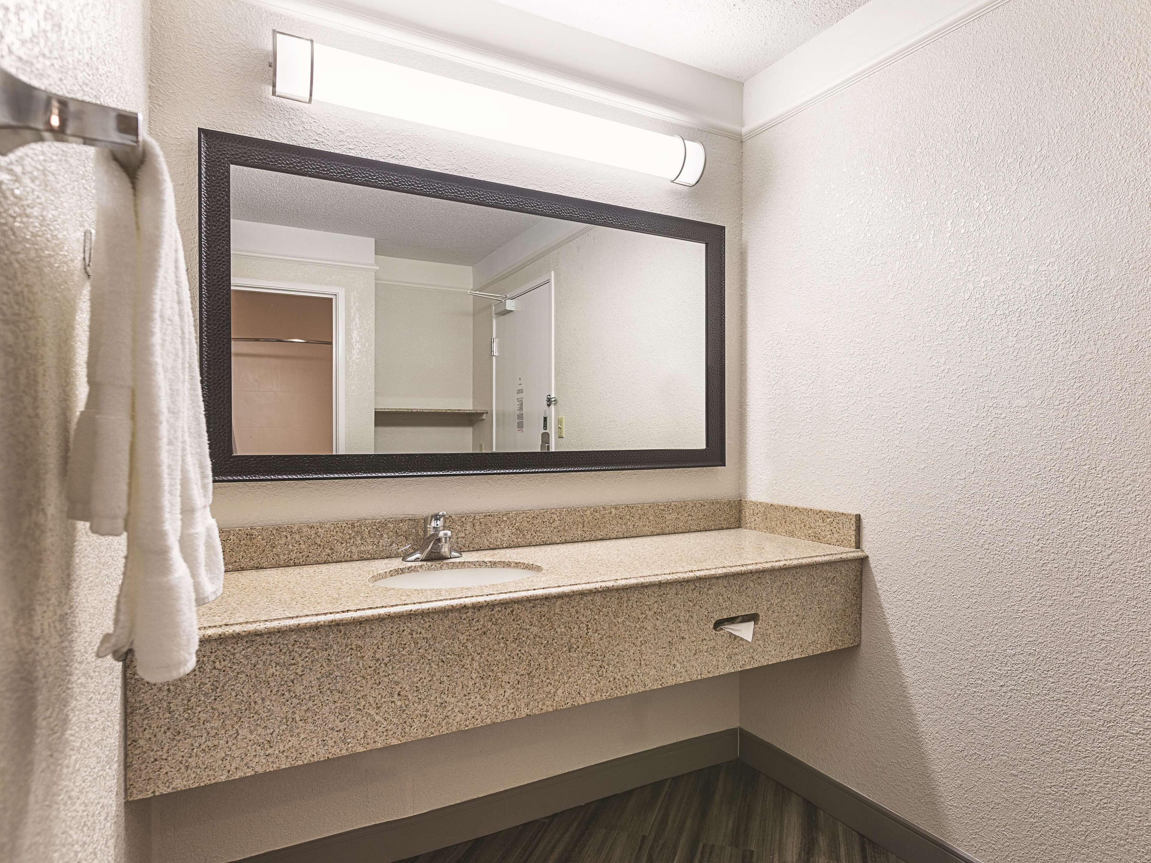 Une salle de bain avec un comptoir en granit, un lavabo, un miroir et un porte-serviettes.