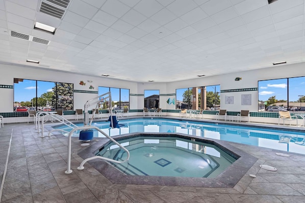 A large indoor swimming pool with clear views of the outside, surrounded by lounge chairs and a tiled floor. - Best Western Plus Twin Falls Hotel (Twin Falls)