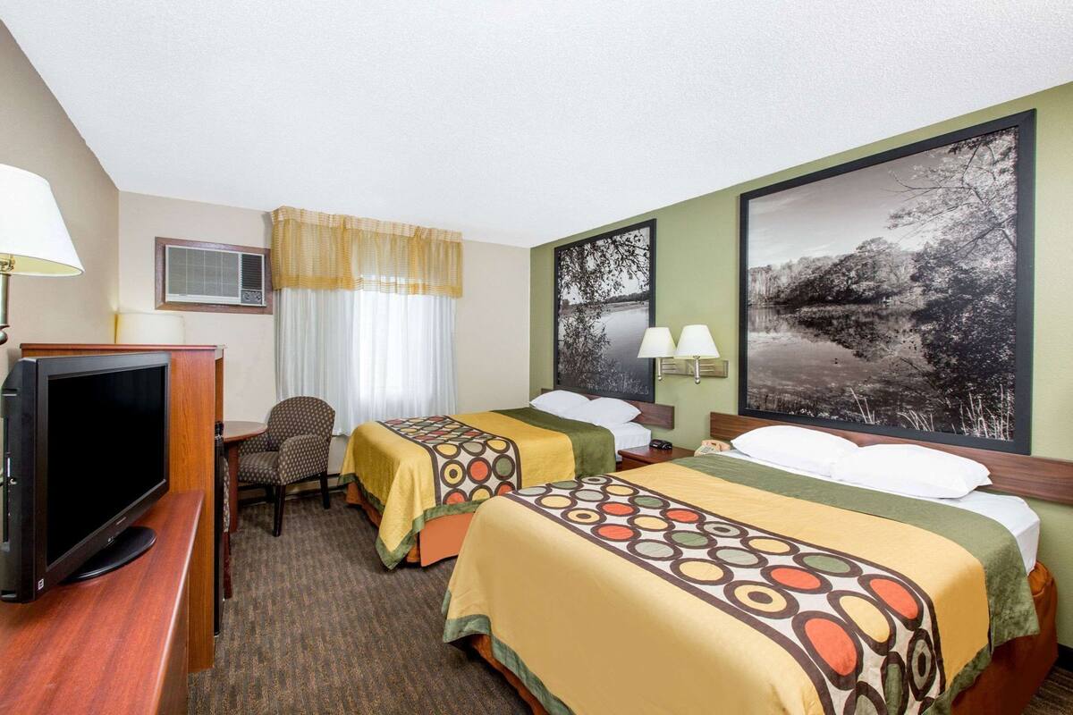 Une chambre d’hôtel avec deux lits, une télévision, un bureau et une chaise.