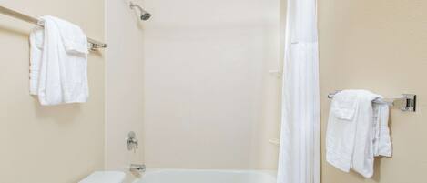 Un baño con una bañera, cortina de ducha y dos toallas colgadas en barras.