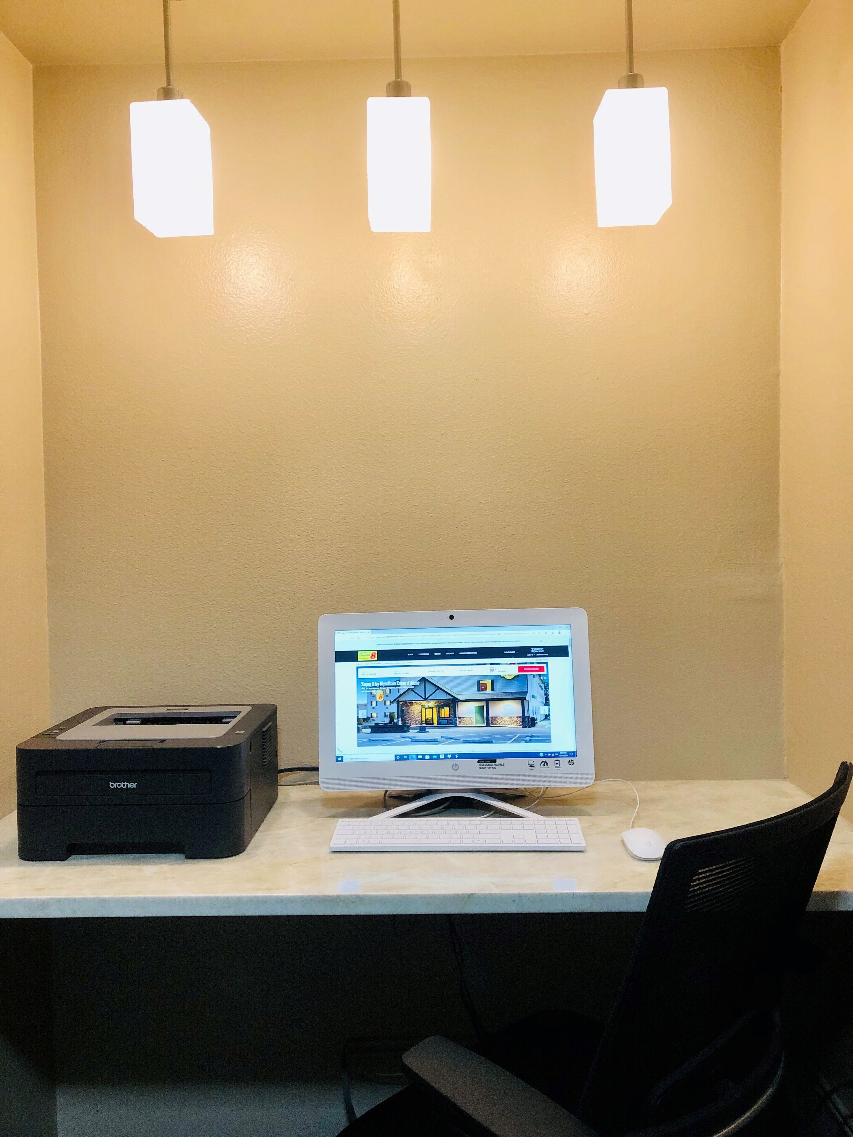 A desk with a desktop computer, a printer, and a chair.