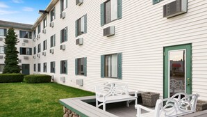 A multi-story building with a covered outdoor seating area, stone steps, and a well-maintained lawn. - Super 8 by Wyndham Coeur d'Alene (Coeur d'Alene)