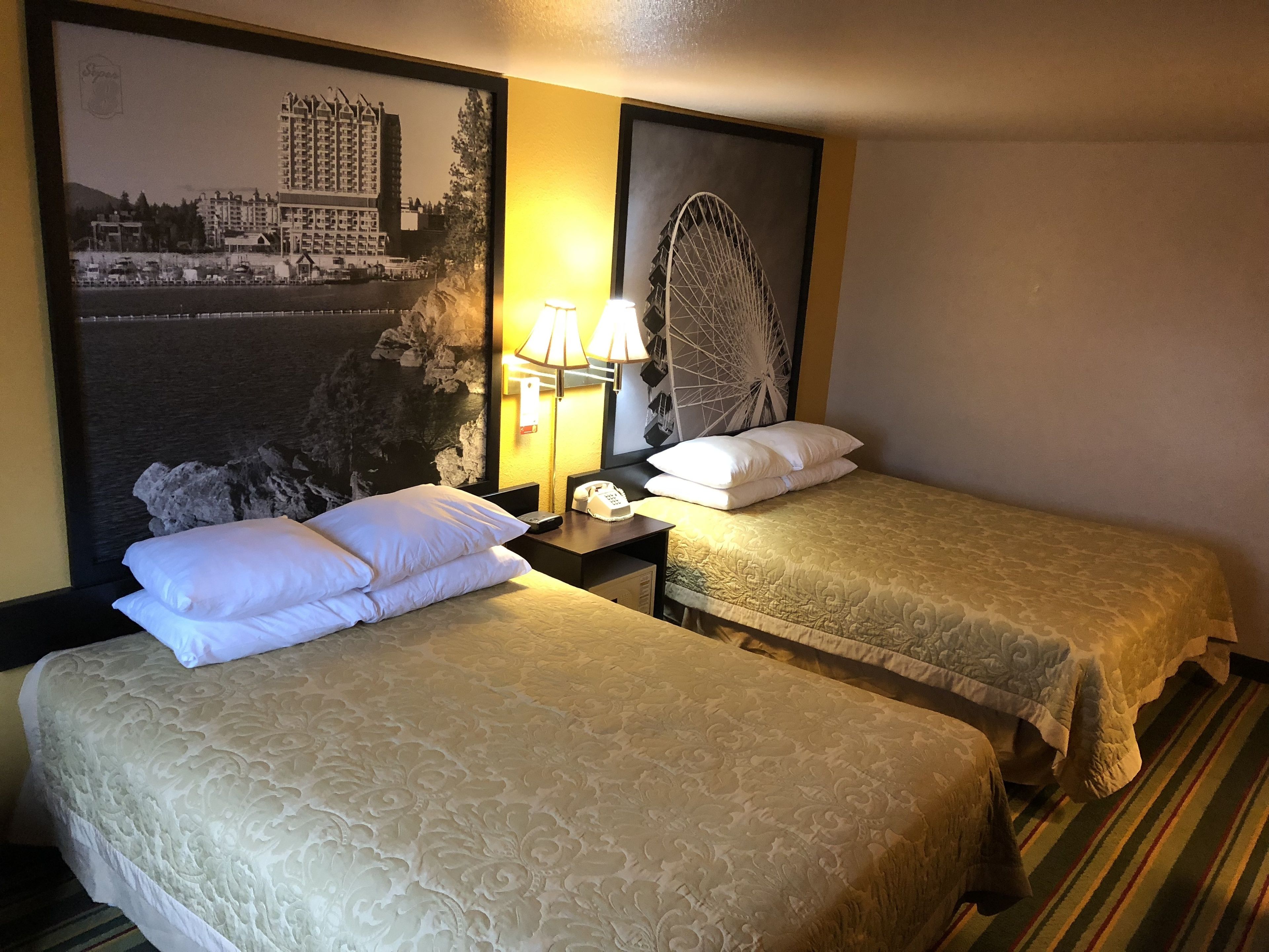 Una habitación de hotel con dos camas, un teléfono en la pared y una lámpara.