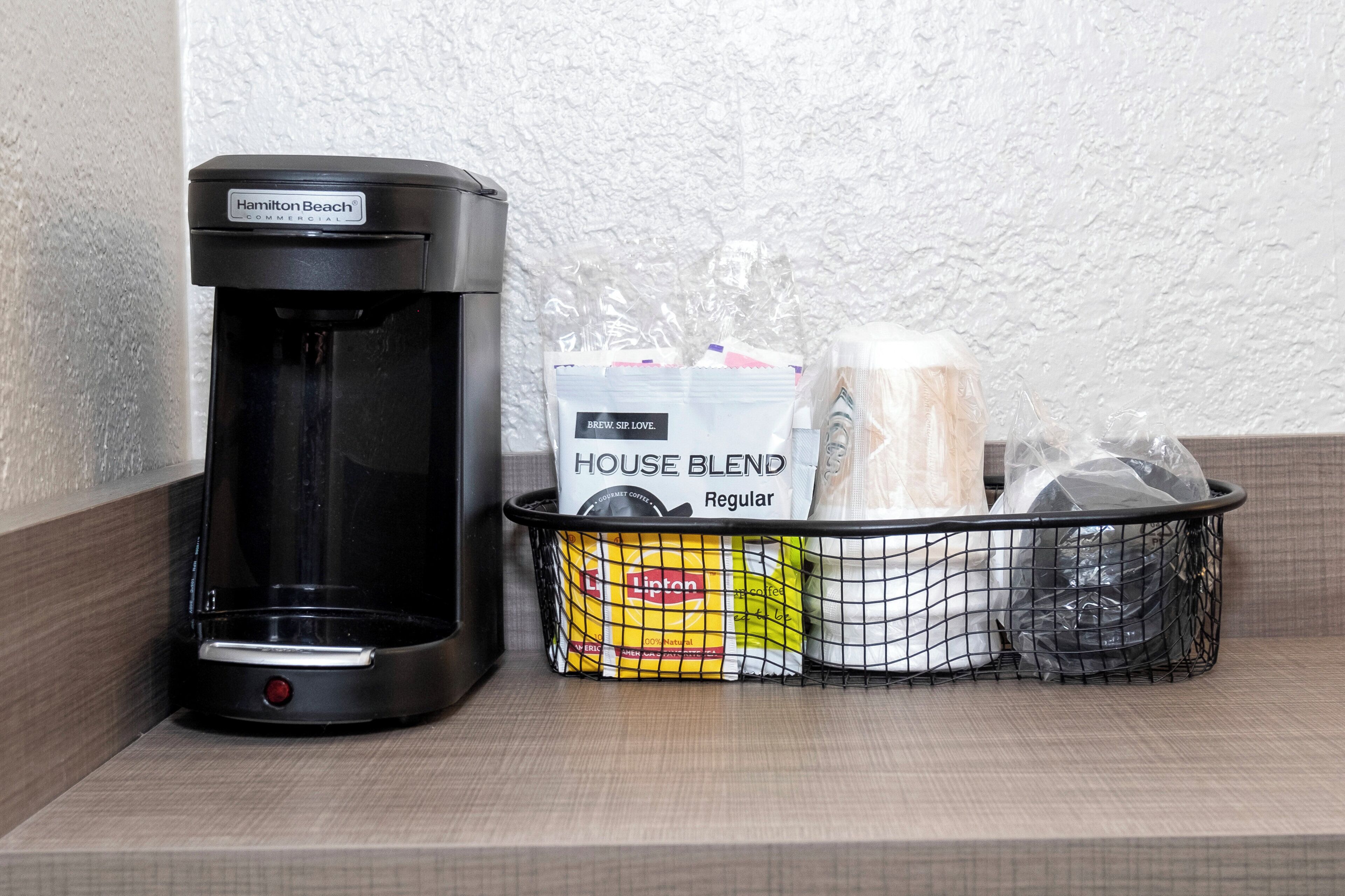 A coffee maker, a coffee bag, and a basket with coffee pods on a countertop.