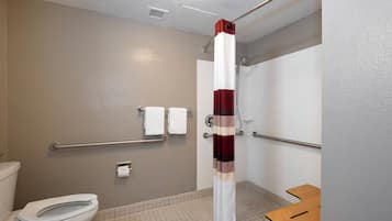 A bathroom with a toilet, a shower with a red and white striped curtain, and a grab bar.