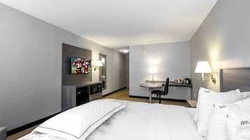 A hotel room with a bed, a desk, a chair, a television, and a microwave.
