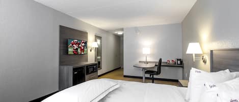 Habitación de hotel con cama, escritorio, silla, televisor y microondas.