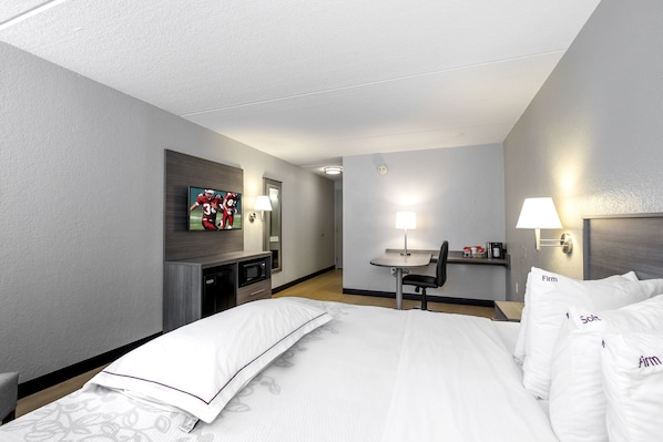 Habitación de hotel con cama, escritorio, silla, televisor y microondas.
