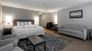 A modern hotel room with a bed, a desk, a sofa, and a small table. - Red Roof Inn PLUS+ Boston - Mansfield/ Foxboro (Mansfield)