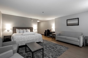 A modern hotel room with a bed, a desk, a sofa, and a small table. - Red Roof Inn PLUS+ Boston - Mansfield/ Foxboro (Mansfield)
