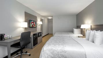 Una habitación de hotel con cama, escritorio con silla, televisor y dos lámparas de noche.