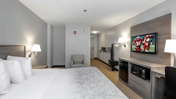 Une chambre d’hôtel avec un grand lit, une télévision, un bureau avec un micro-ondes et une chaise.