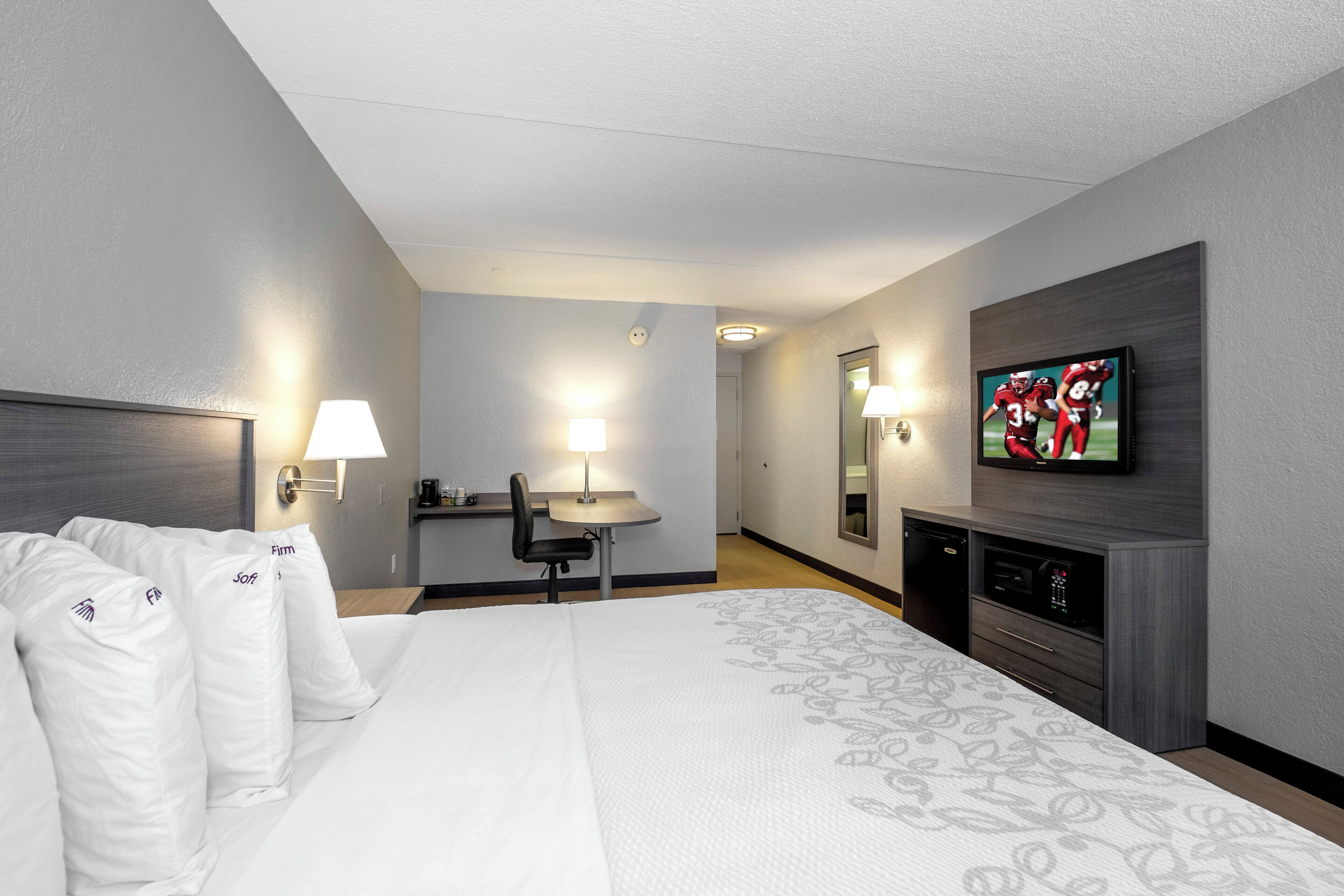 Habitación de hotel con cama, escritorio, silla, televisor y minibar.