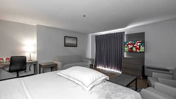 A hotel room with a bed, a desk, a chair, a television, and a window with curtains.