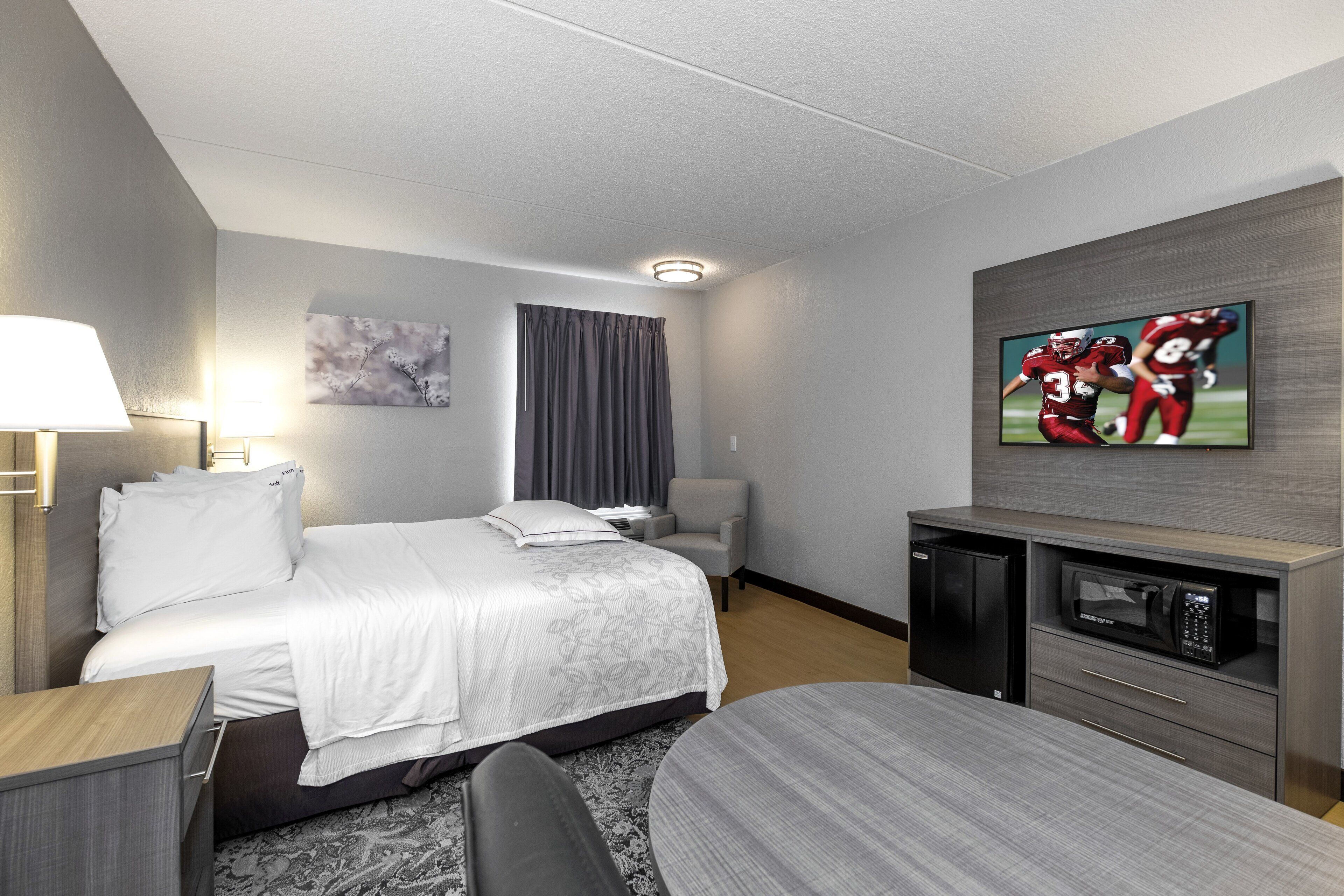 Ein Hotelzimmer mit Bett, Fernseher, Schreibtisch und Stuhl.